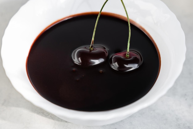 Bagas de cereja em calda de chocolate em uma tigela branca, reflexo de calda de chocolate. Foto de alta qualidade