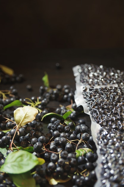 Bagas de chokeberry (Aronia melanocarpa) são embaladas em sacos a vácuo e bagas pretas na mesa escura.