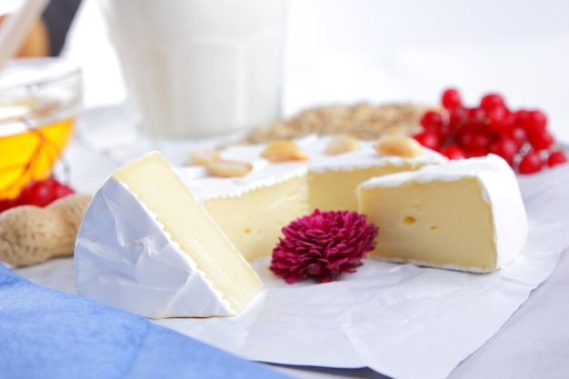 Bagas de nozes de camembert e biscoitos com sementes em papel manteiga branco Queijo com mel um copo de leite e um guardanapo azul e branco sobre um fundo claro Closeup