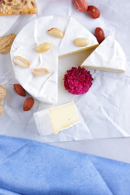 Bagas de nozes de camembert e biscoitos com sementes em papel manteiga branco Queijo com mel um copo de leite e um guardanapo azul e branco sobre um fundo claro Closeup