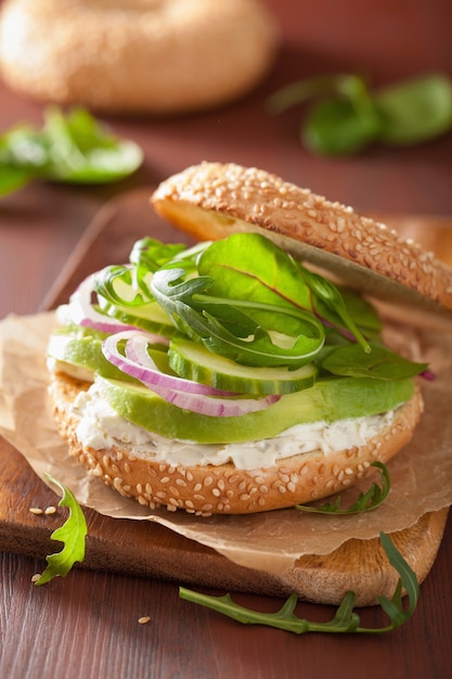 Bagel de aguacate con queso crema, cebolla, pepino y rúcula