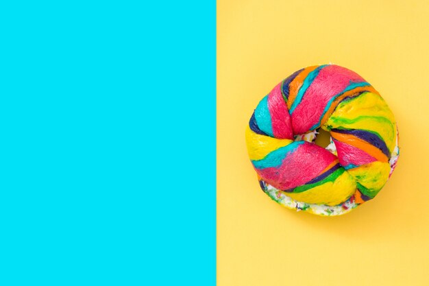 Bagel colorido sobre fundo azul e amarelo. Copie o espaço