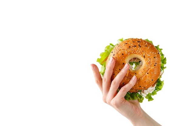 Bagel com cream cheese na mão de uma mulher segurando um sanduíche com alface no café da manhã Espaço para texto