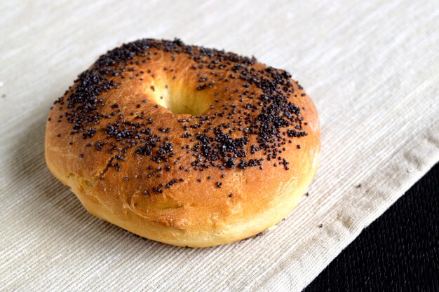 Foto bagel com sementes de papoila em um guardanapo de linho leve.