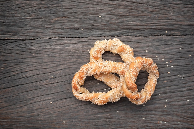 Bagel espiral con semillas de sésamo sobre mesa de madera oscura.