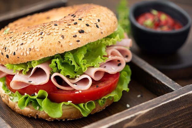 Bagel con jamón, lechuga, tomate y salsa de tomate.