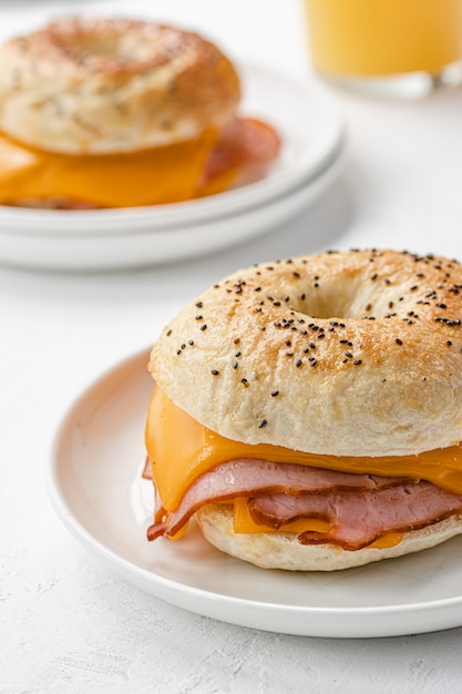 Bagel mit Schinken und Cheddar-Käse auf weißem Teller