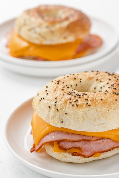 Bagel mit Schinken und Cheddar-Käse auf weißem Teller