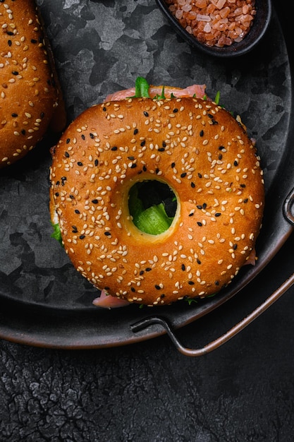 Bagel con pescado rojo y queso blando sobre fondo de mesa de piedra oscura negra vista superior plana