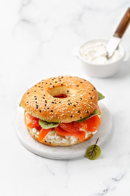 Bagel con queso crema de salmón y micro verduras a bordo y fondo de mármol