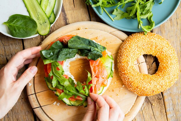 Bagel con salmón. Chica está preparando un sándwich para el desayuno.