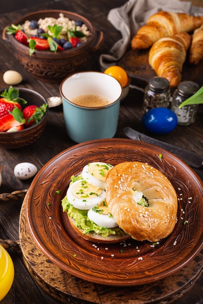 Bagel saludable recién horneado relleno de huevos duros, aguacate y cebollino. Comida de desayuno