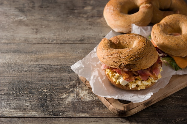 Bagel sandwich con tocino, huevo y queso en mesa de madera copyspace