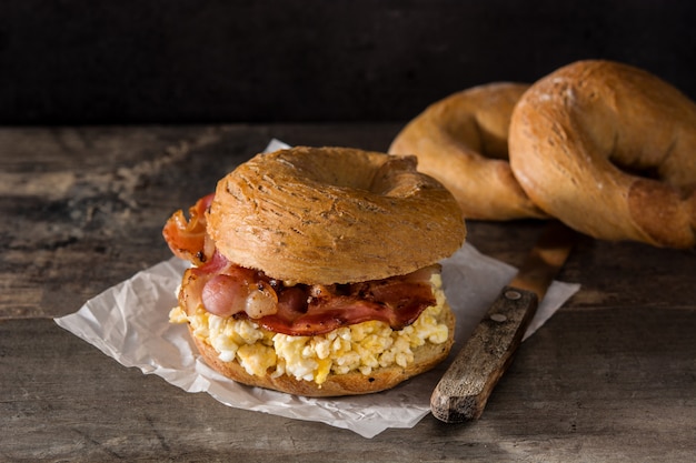 Bagel sandwich con tocino, huevo y queso en la mesa de madera.