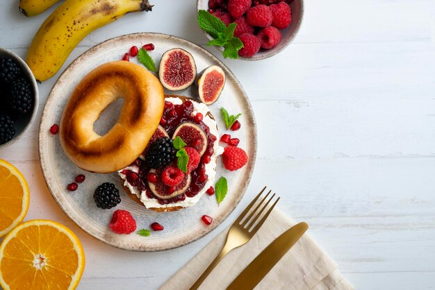 Foto bagel tostado con frutos rojos e higos con crema de queso. desayuno o brunch muy saludable.