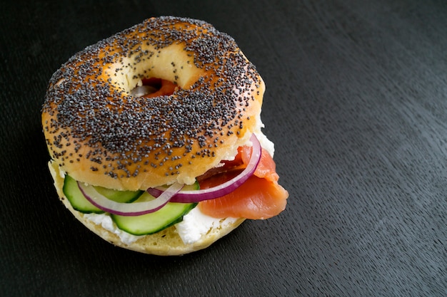 Bagels com cream cheese e salmão defumado em um fundo preto