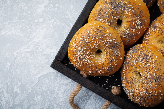 Bagels frescos de grãos integrais de variedade com sementes de papoila, sementes de gergelim sobre fundo claro concreto