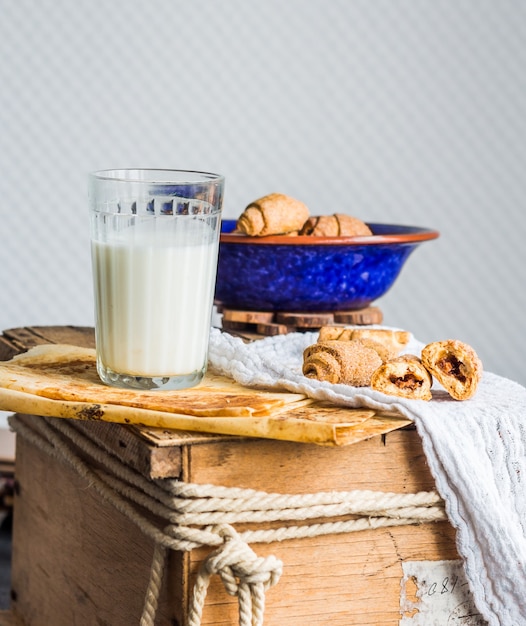 Bagels galletas de masa con relleno, leche, en la placa azul pasteles dulces en madera