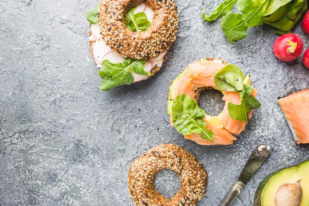 Bagels mit Frischkäse-Avocado, Fisch, Rucola und Rettich. Gesunde Frühstücksnahrung. Ansicht von oben.