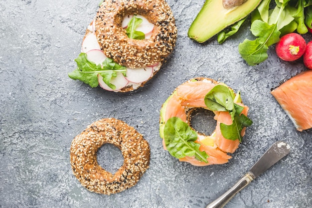 Bagels mit Frischkäse-Avocado, Fisch, Rucola und Rettich. Gesunde Frühstücksnahrung. Ansicht von oben.