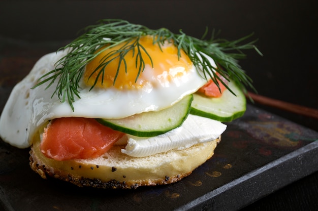 Bagels mit Frischkäse und geräuchertem Lachs auf einem schwarzen Hintergrund