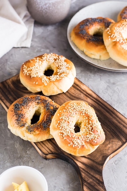 Bagels con semillas de amapola y sésamo en el tablero y mantequilla en un recipiente sobre la mesa Vista vertical