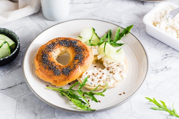 Bagelsandwich mit Frischkäsegurke und Rucola auf einem Teller auf dem Tisch Hausgemachtes Frühstück