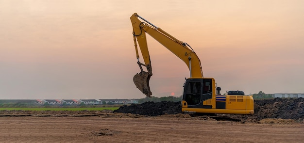 Bagger, der auf der Baustelle bei Sonnenuntergang arbeitet