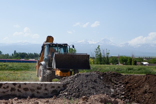 Bagger und Neubau im Feld. ein Haus bauen