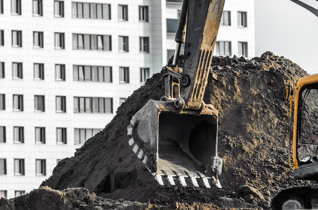 Baggerarbeiten vor Ort auf dem Hintergrund von mehrstöckigen Häusern.