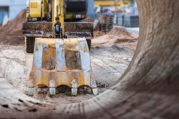 Baggerschaufel Nahaufnahme gegen den blauen Himmel gräbt den Boden Erdarbeiten mit schwerem Gerät auf der Baustelle