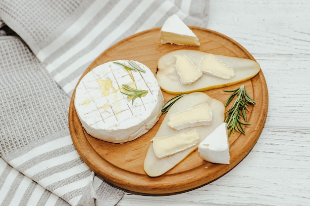 Baguete branca cortada em pedaços com azeite e queijo Camembert em cima da mesa