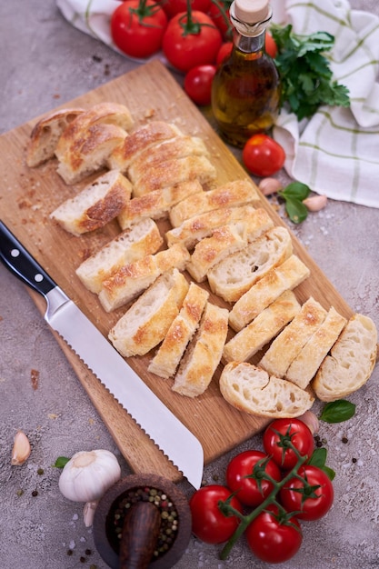 Baguete de pão francês fatiado na tábua de pão de madeira