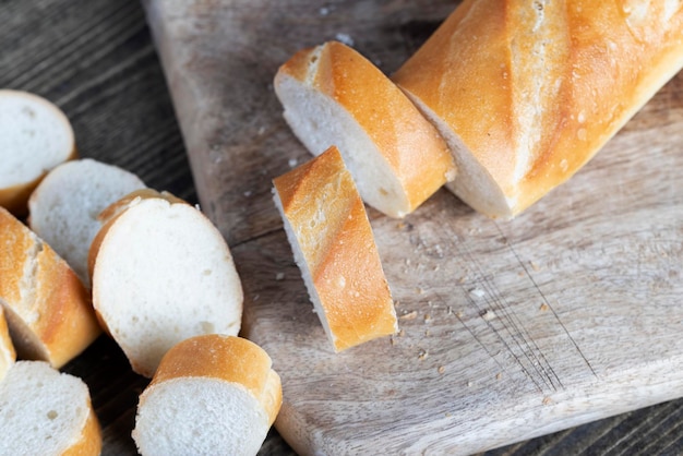 Baguete de trigo cortada em pedaços em uma tábua de corte