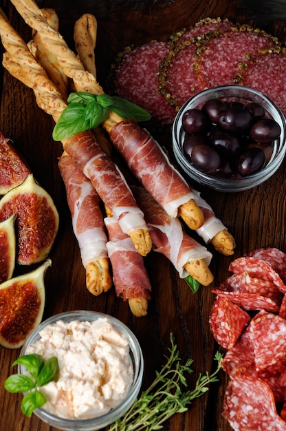 baguetes com parmesão embrulhado com uma fatia de antepasto de presunto e figo em uma mesa de madeira