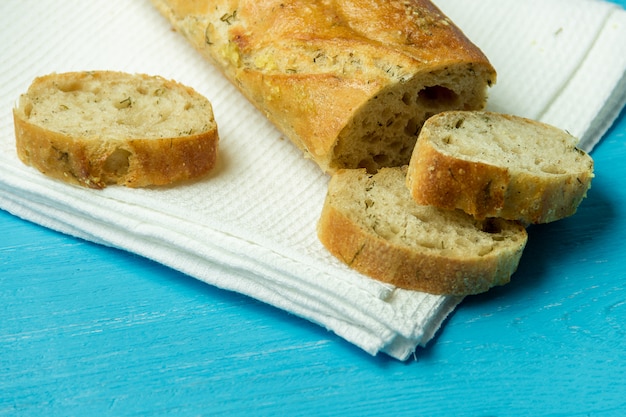 Baguette de ajo sobre papel de cocina blanco sobre mesa de madera.