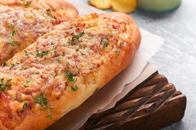 Baguette-Boote Heiß gebackenes Sandwich auf Baguette-Brot mit Schinken-Speck-Gemüse und Käse auf Pergament und Holzständer auf grauem Betongrund Draufsicht Kopierbereich