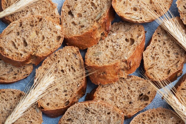 Baguette de centeno en rodajas sobre una superficie gris con cereales. Pan integral, un concepto de comida saludable. De cerca.