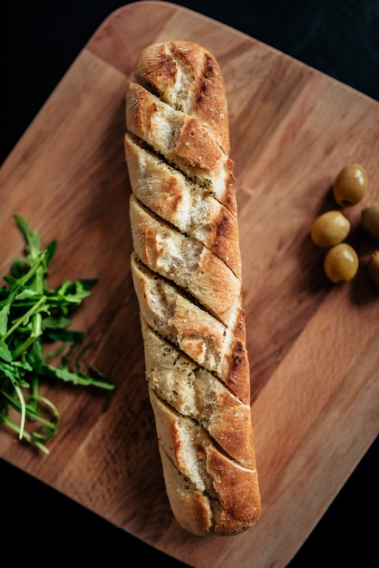 Baguette cortado en un tablero de madera, vista superior.