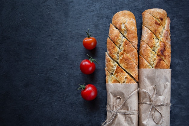 Baguette francés y tomates cherry sobre un fondo oscuro