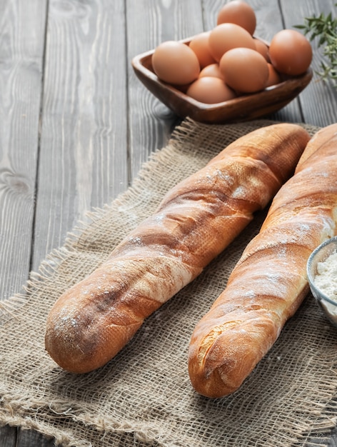 Baguette francesa fresca hecha de harina blanca junto a huevos de gallina y harina