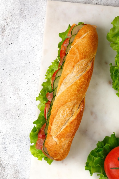 Baguette con jamón y verduras Sándwich con jamón tomate ensalada de lechuga pepino Vista superior