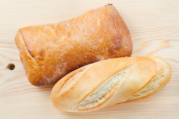 Baguette y pan recién horneados en la vista superior de la tabla de cortar de madera