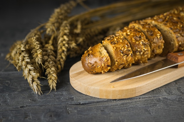 Baguette en rodajas es de color marrón dorado en tabla de cortar en mesa de madera