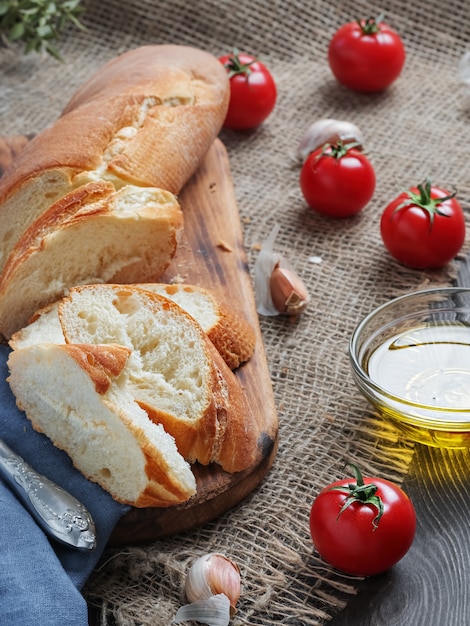 Baguette en rodajas frescas, tomates y aceite de oliva, ingredientes para hacer un sándwich