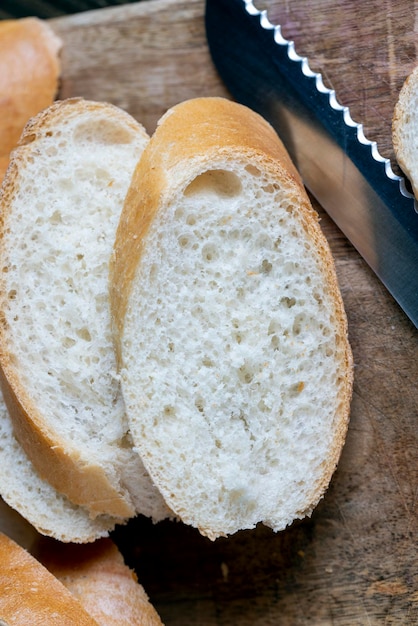 Baguette de trigo cortado en trozos en una tabla de cortar baguette de trigo blanco cortado en rodajas durante la cocción