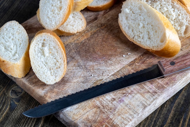 Baguette de trigo cortado en trozos en una tabla para cortar