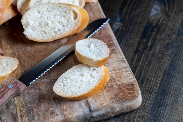 Baguette de trigo cortado en trozos en una tabla para cortar