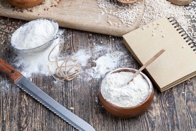 Una baguette de trigo en la mesa con harina y varios granos de plantas una mesa de cocina con pan e ingredientes para papilla y arroz