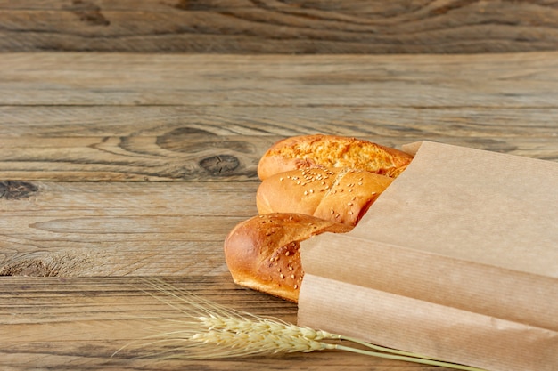 Baguettes francesas dispuestas en bolsa de papel y trigo sobre una mesa de madera rústica.